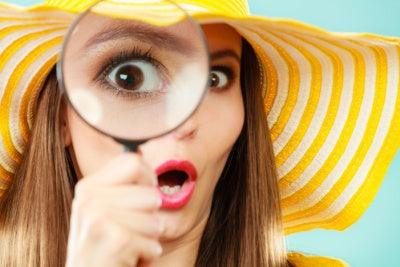 Attractive woman looking for answers with a magnifying glass.