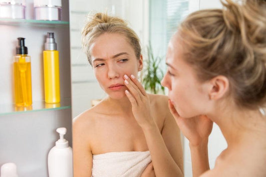 Woman Examining skin in bathroom mirror