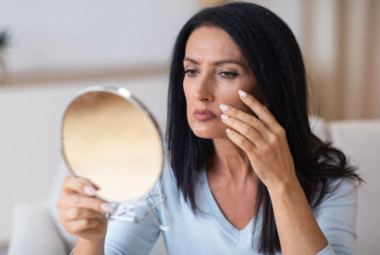 Mature woman examining her face in a mirror.