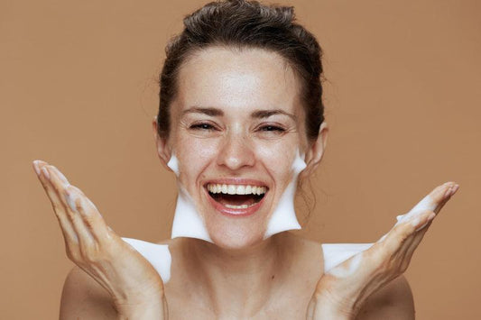 Woman using facial cleanser and smiling